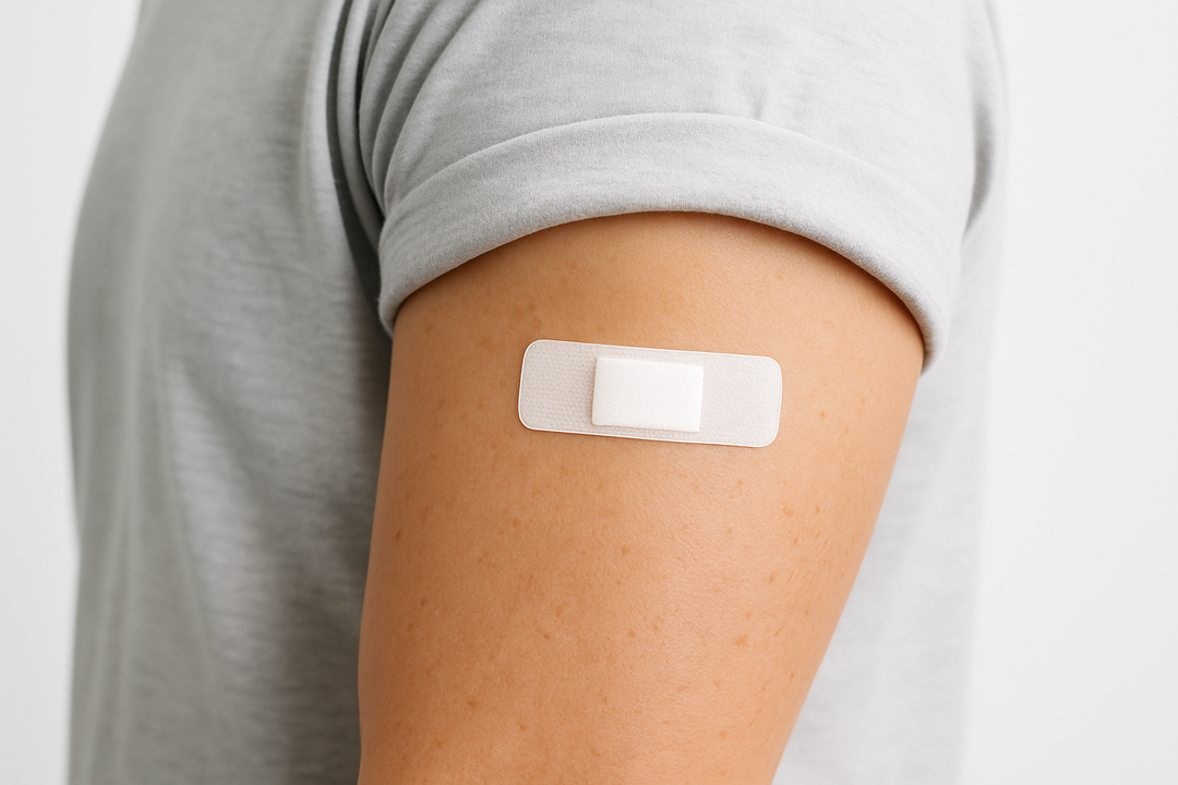 show an arm with up rolled t-shirt sleeve with a small white bandaid covering a vaccine spot